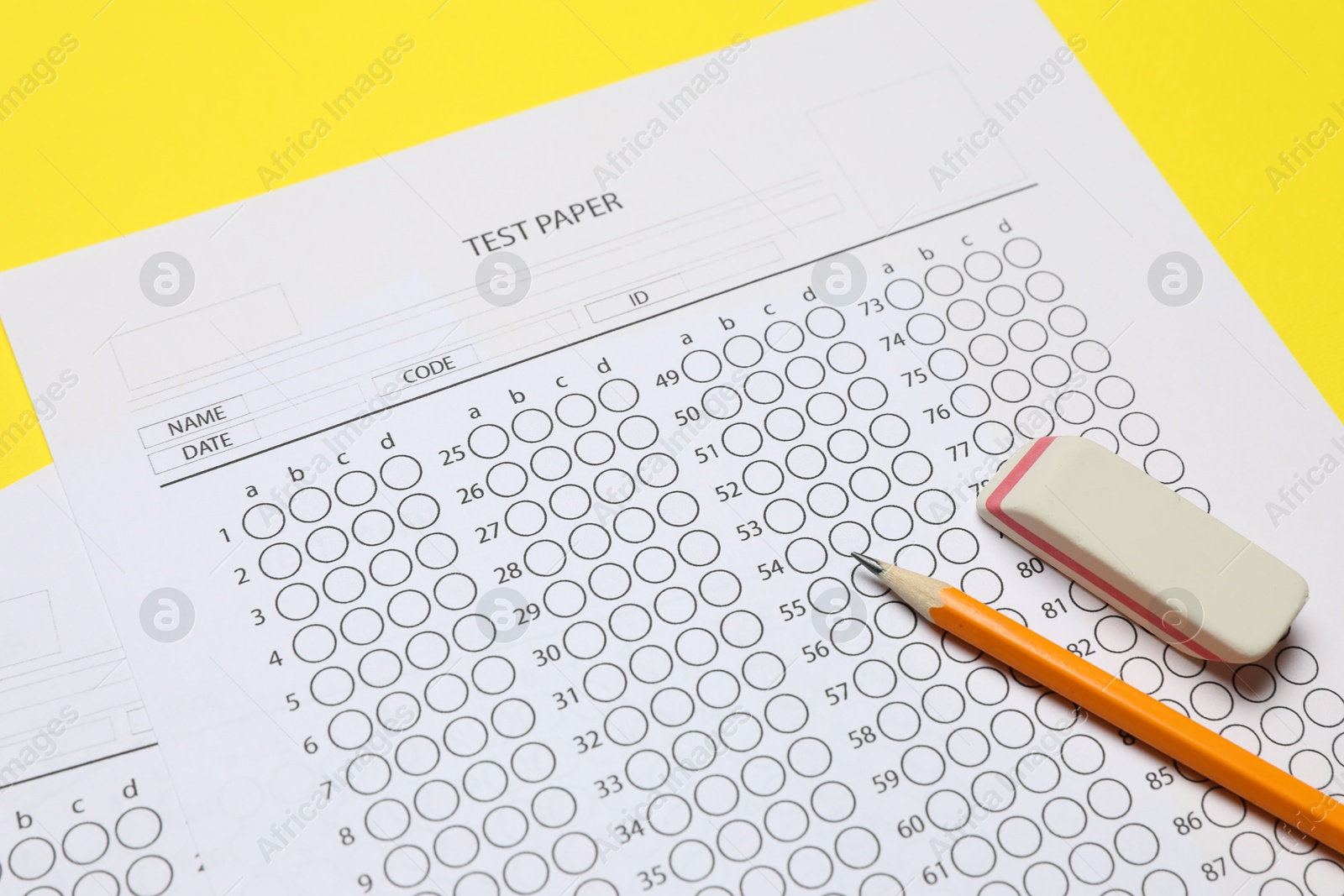 Photo of Answer sheet, pencil and eraser on yellow background, closeup. Student passing exam