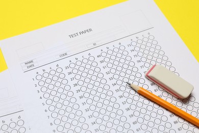 Photo of Answer sheet, pencil and eraser on yellow background, closeup. Student passing exam