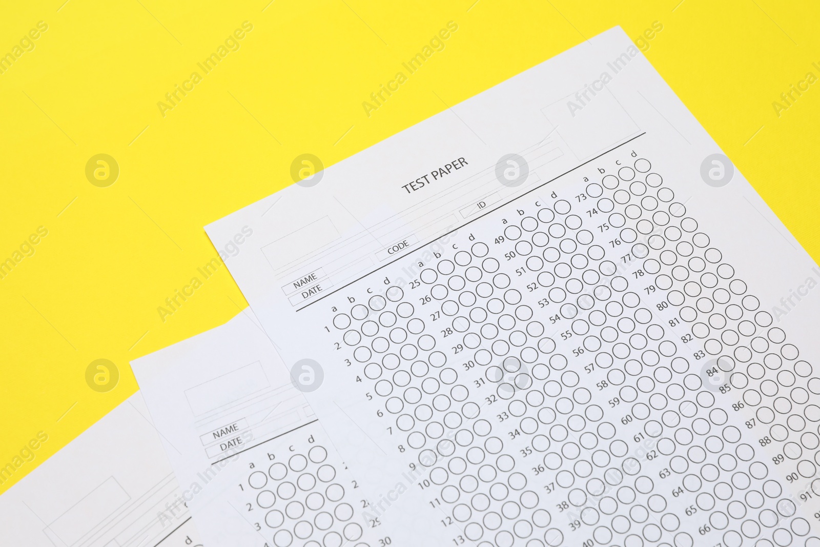 Photo of Answer sheets on yellow background, above view. Student passing exam