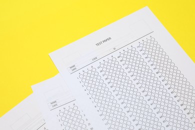 Photo of Answer sheets on yellow background, above view. Student passing exam