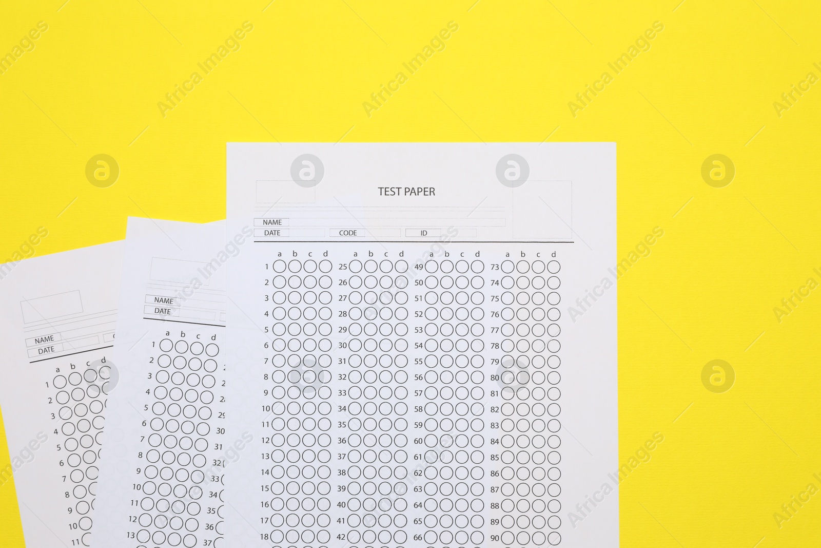 Photo of Answer sheets on yellow background, flat lay. Student passing exam