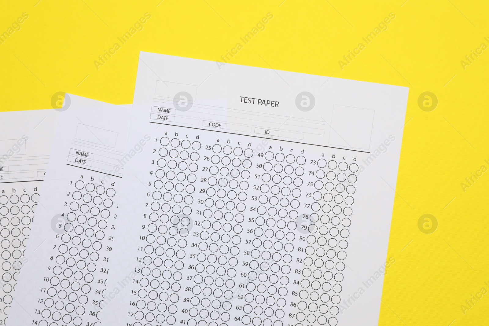 Photo of Answer sheets on yellow background, flat lay. Student passing exam