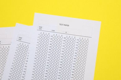 Photo of Answer sheets on yellow background, flat lay. Student passing exam