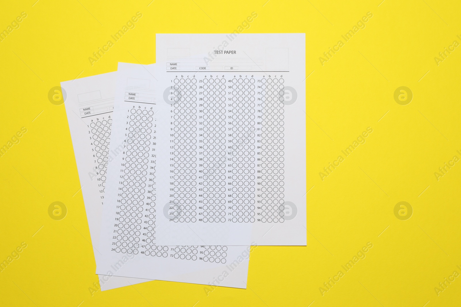 Photo of Answer sheets on yellow background, flat lay. Student passing exam