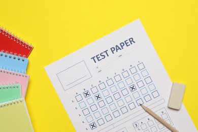 Photo of Answer sheet, pencil and eraser and notebooks on yellow background, flat lay. Student passing exam