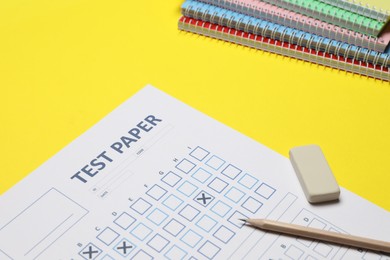 Photo of Answer sheet, pencil and eraser and notebooks on yellow background, closeup. Student passing exam