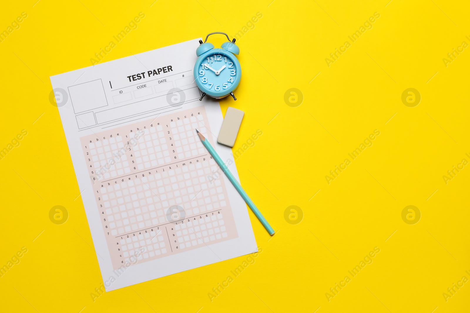Photo of Student passing exam. Answer sheet, alarm clock, pencil and eraser on yellow background, flat lay. Space for text