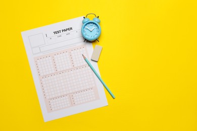 Photo of Student passing exam. Answer sheet, alarm clock, pencil and eraser on yellow background, flat lay. Space for text
