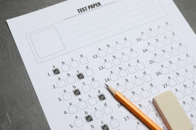 Photo of Answer sheet, pencil and eraser on gray textured table, closeup. Student passing exam