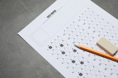 Photo of Answer sheet, pencil and eraser on gray textured table, closeup. Student passing exam