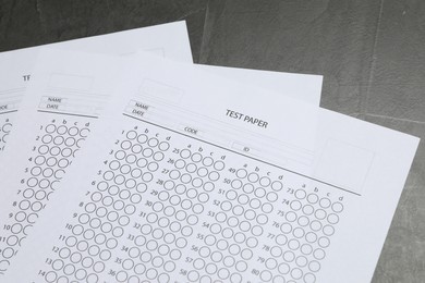 Photo of Answer sheets on gray textured table, closeup. Student passing exam