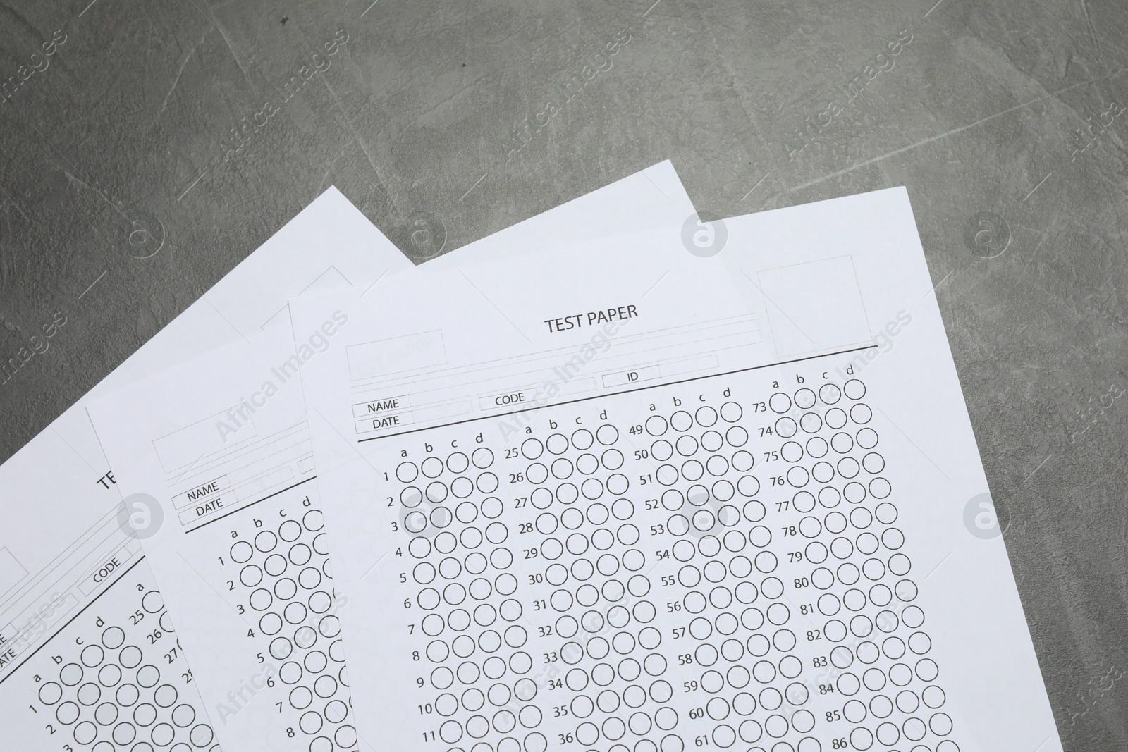 Photo of Answer sheets on gray textured table, flat lay. Student passing exam