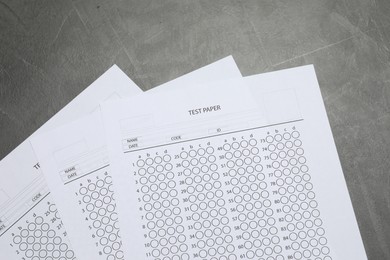 Photo of Answer sheets on gray textured table, flat lay. Student passing exam