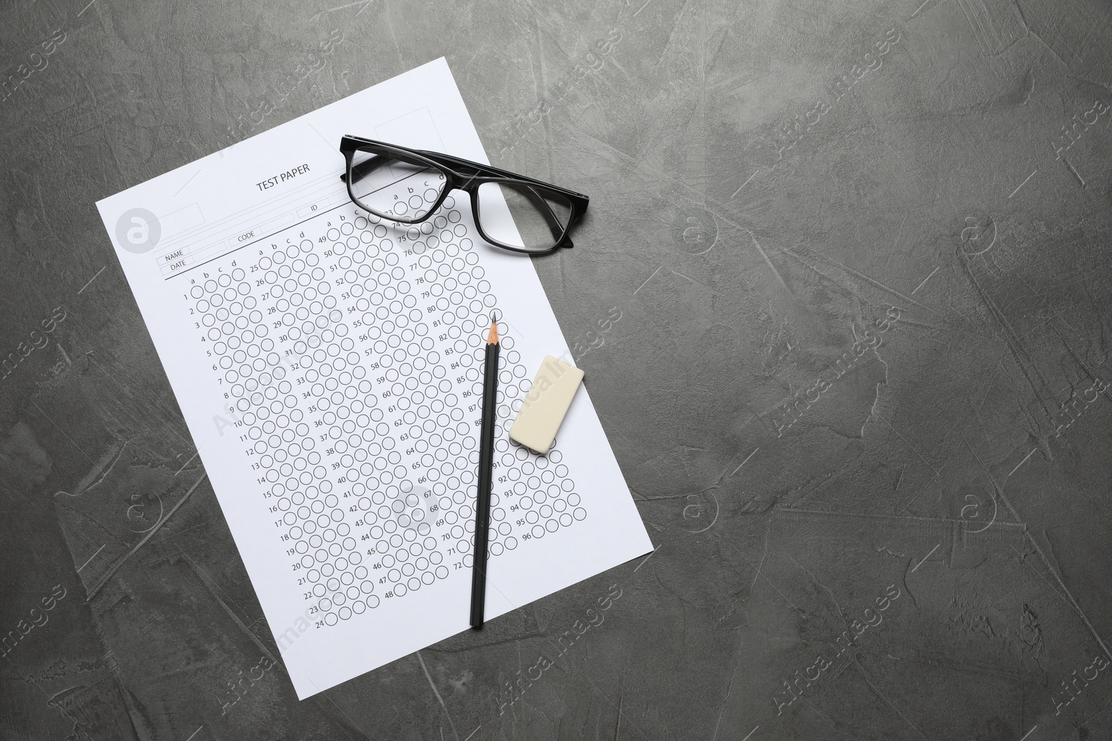Student passing exam. Answer sheet, glasses, pencil and eraser on gray textured table, flat lay. Space for text Photo of Student passing exam. Answer sheet, glasses, pencil and eraser on gray textured table, flat lay. Space for text