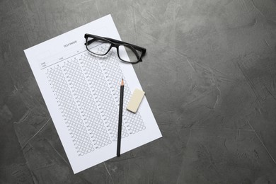 Photo of Student passing exam. Answer sheet, glasses, pencil and eraser on gray textured table, flat lay. Space for text