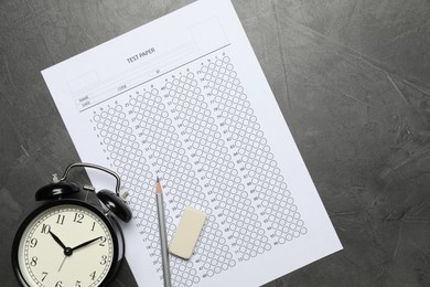 Photo of Answer sheet, alarm clock, pencil and eraser on gray textured table, flat lay. Student passing exam