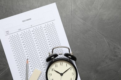 Photo of Student passing exam. Answer sheet, alarm clock, pencil and eraser on gray textured table, flat lay. Space for text