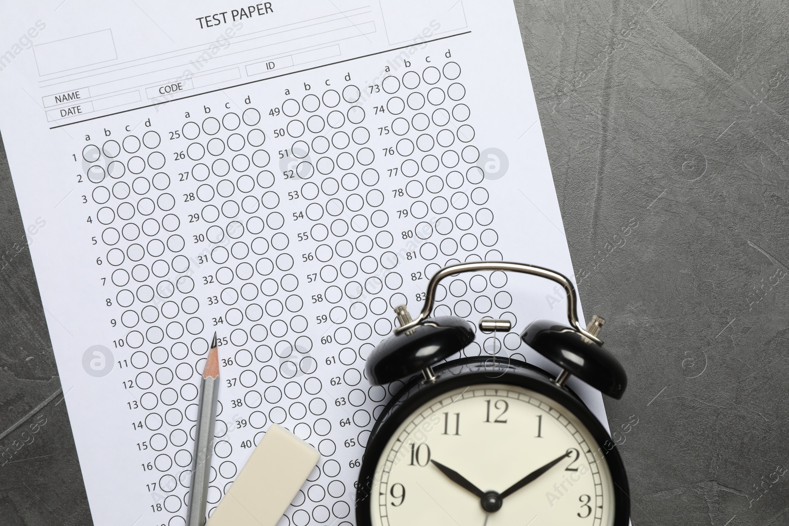Photo of Answer sheet, alarm clock, pencil and eraser on gray textured table, flat lay. Student passing exam