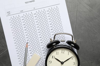 Photo of Answer sheet, alarm clock, pencil and eraser on gray textured table, flat lay. Student passing exam