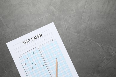 Photo of Student passing exam. Answer sheet and pencil on gray textured table, flat lay. Space for text