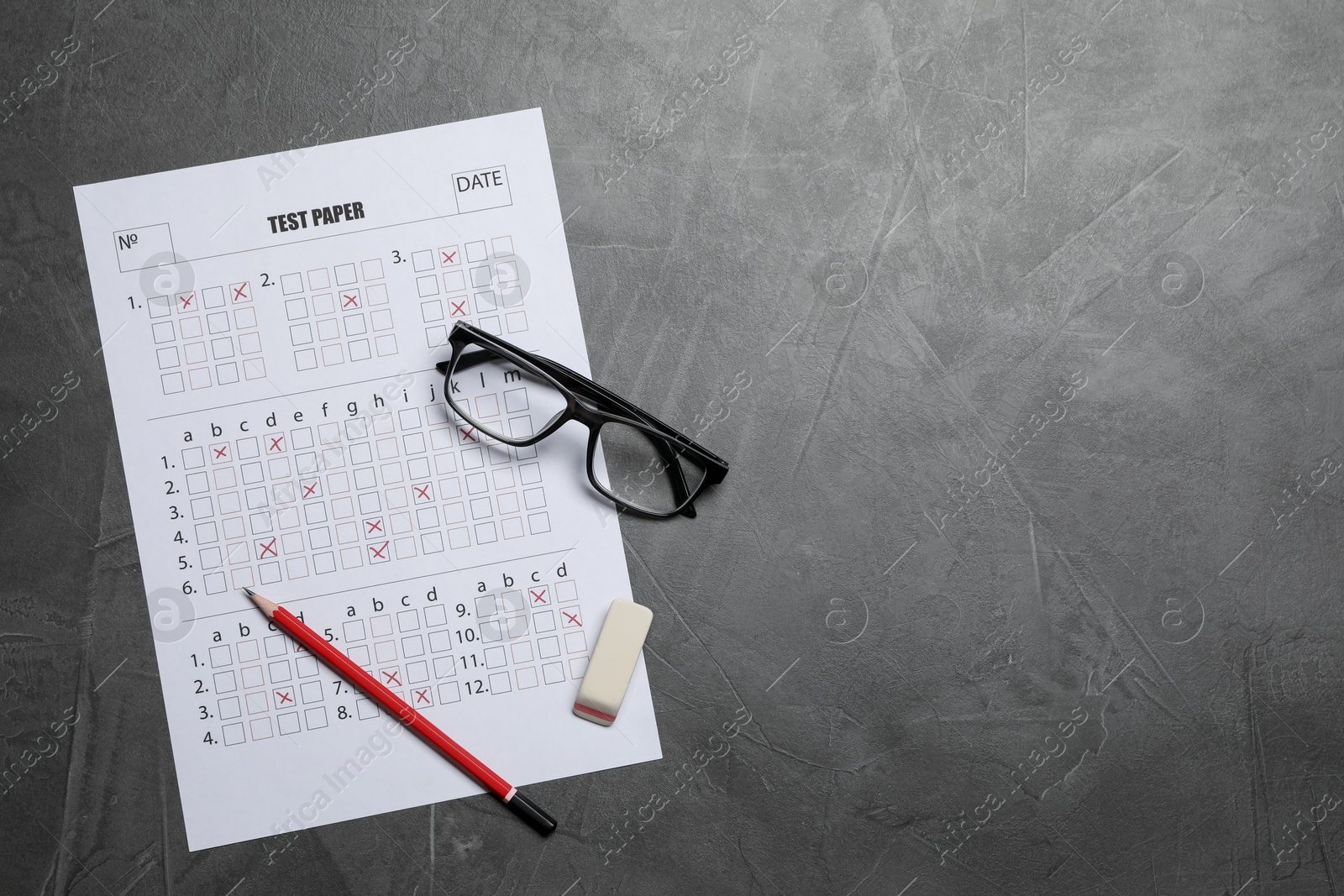 Student passing exam. Answer sheet, glasses, pencil and eraser on gray textured table, flat lay. Space for text Photo of Student passing exam. Answer sheet, glasses, pencil and eraser on gray textured table, flat lay. Space for text
