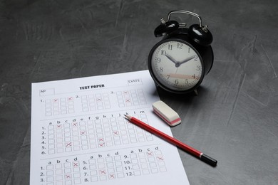 Photo of Answer sheet, alarm clock, pencil and eraser on gray textured table, closeup. Student passing exam