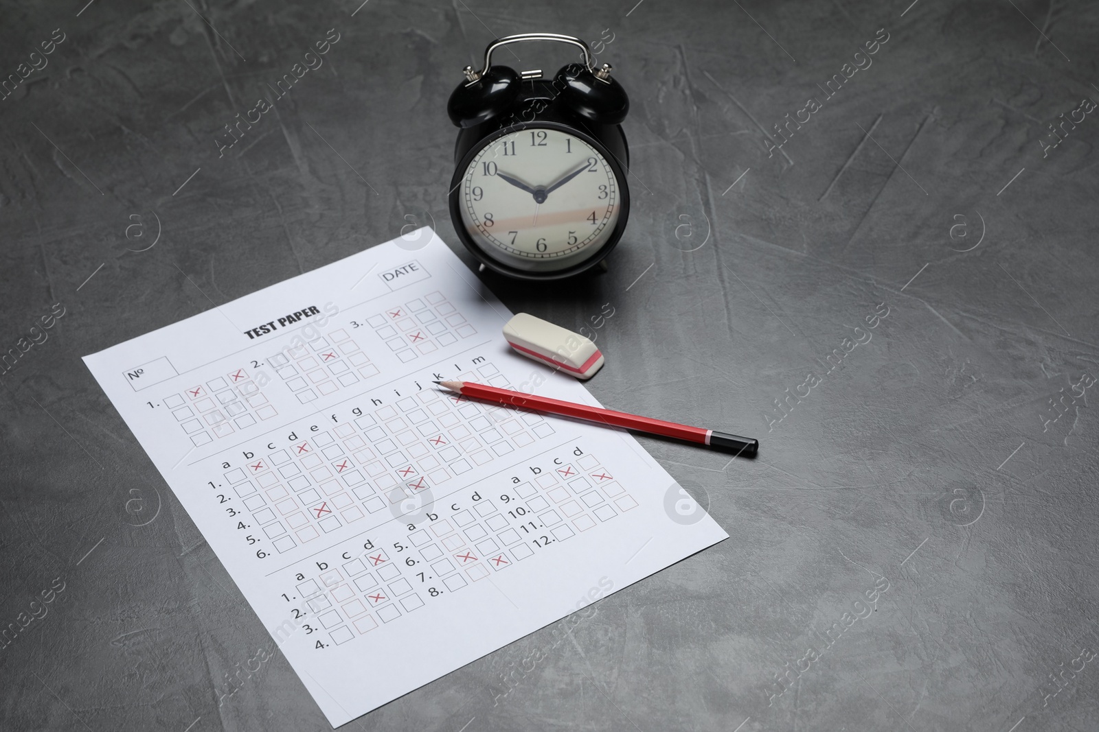Answer sheet, alarm clock, pencil and eraser on gray textured table. Student passing exam Photo of Answer sheet, alarm clock, pencil and eraser on gray textured table. Student passing exam