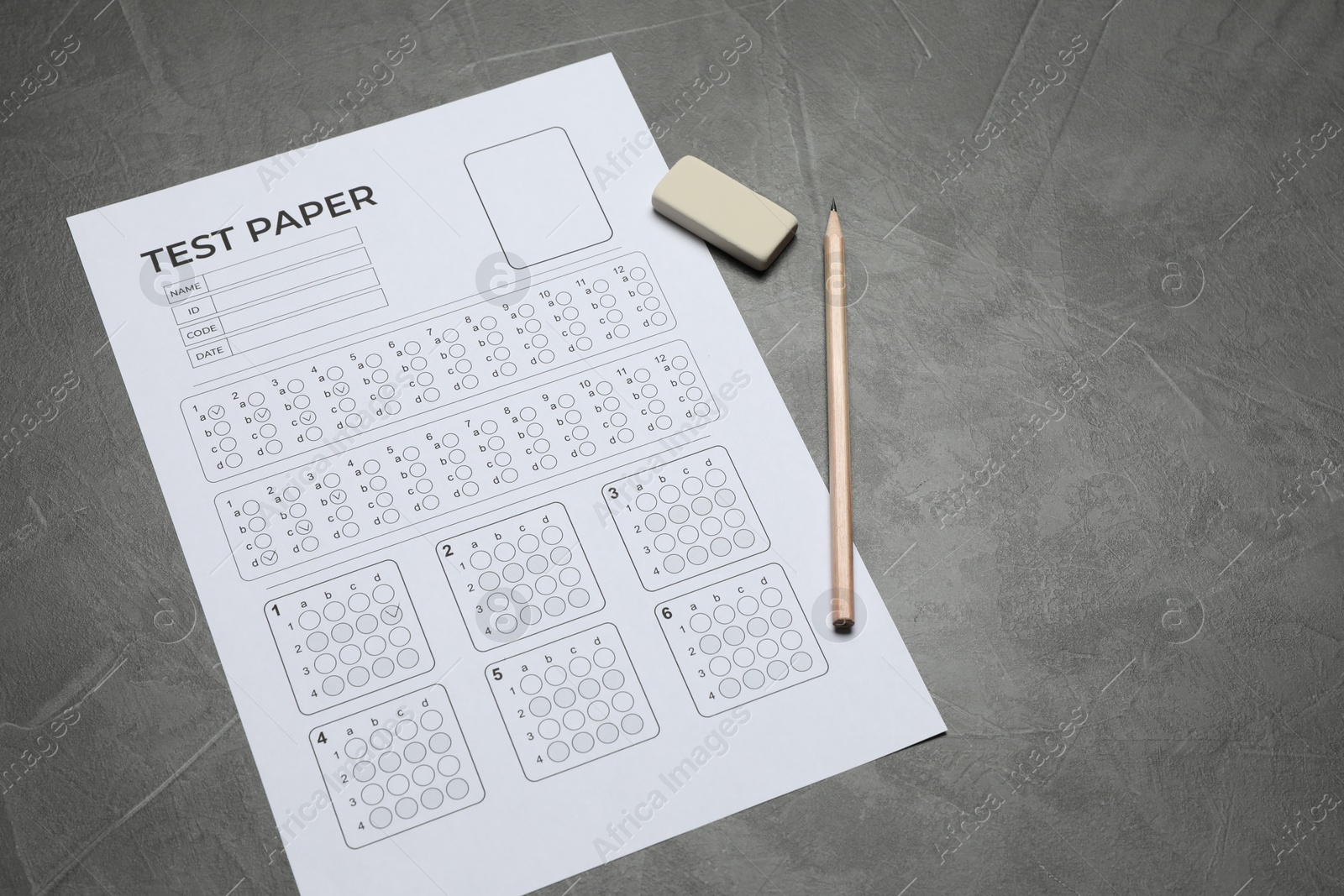 Answer sheet, pencil and eraser on gray textured table, above view. Student passing exam Photo of Answer sheet, pencil and eraser on gray textured table, above view. Student passing exam