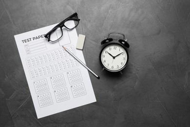 Photo of Answer sheet, alarm clock, glasses, pencil and eraser on gray textured table, flat lay. Student passing exam