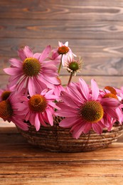 Photo of Beautiful Echinacea flowers in wicker basket on wooden table