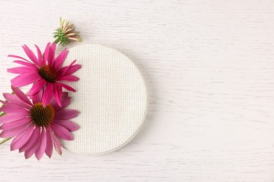 Photo of Beautiful Echinacea flowers and podium on light wooden table, flat lay. Space for text