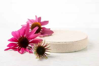 Photo of Beautiful Echinacea flowers and podium on light wooden table against white background, closeup. Space for text