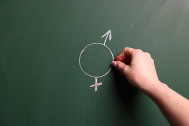 Photo of Sex Education. Woman drawing gender symbol on green chalkboard, closeup