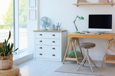 Photo of Home workspace. Modern computer and stationery on wooden desk near window indoors