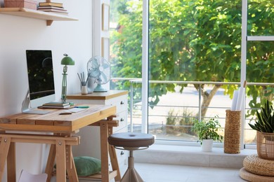 Photo of Home workspace. Modern computer and stationery on wooden desk near window indoors