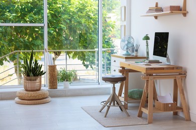 Photo of Home workspace. Modern computer and stationery on wooden desk near window indoors