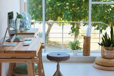Photo of Home workspace. Modern computer and stationery on wooden desk near window indoors