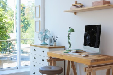 Photo of Home workspace. Modern computer and stationery on wooden desk near window indoors
