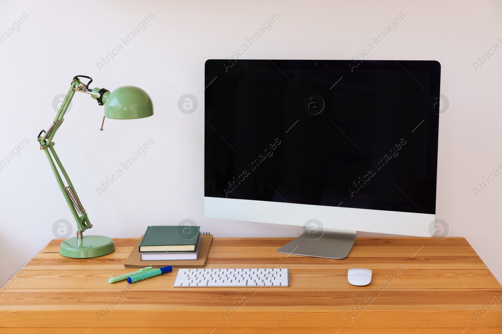 Photo of Home workspace. Modern computer, lamp and stationery on wooden desk indoors
