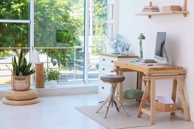 Photo of Home workspace. Modern computer and stationery on wooden desk near window indoors