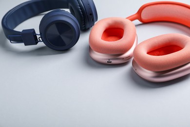 Photo of Different stylish headphones on light grey background, closeup. Space for text