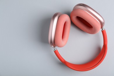 Photo of Pair of stylish pink headphones on light grey background, top view. Space for text