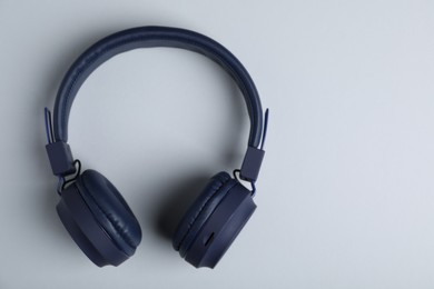 Photo of Pair of stylish blue headphones on light grey background, top view. Space for text
