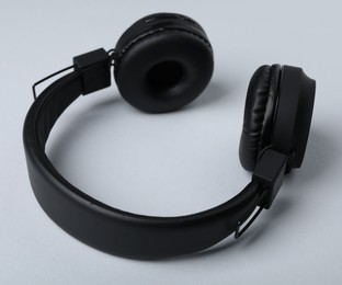 Photo of Pair of stylish black headphones on light grey background, closeup