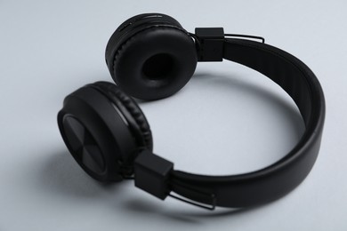 Photo of Pair of stylish black headphones on light grey background, closeup