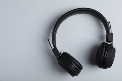 Photo of Pair of stylish black headphones on light grey background, top view. Space for text