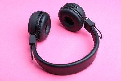 Photo of Pair of stylish black headphones on pink background