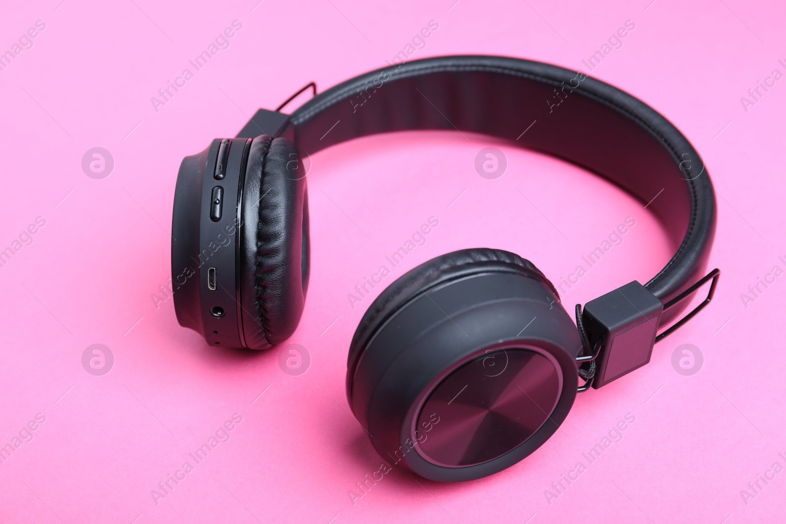 Pair of stylish black headphones on pink background Photo of Pair of stylish black headphones on pink background
