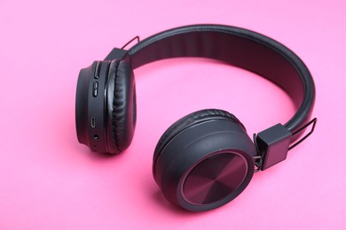 Photo of Pair of stylish black headphones on pink background