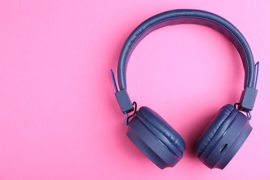 Photo of Pair of stylish blue headphones on pink background, top view. Space for text